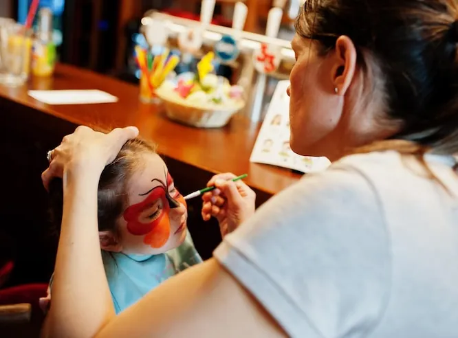 A girl having a red butterfly painted on her face with face-painting colours
